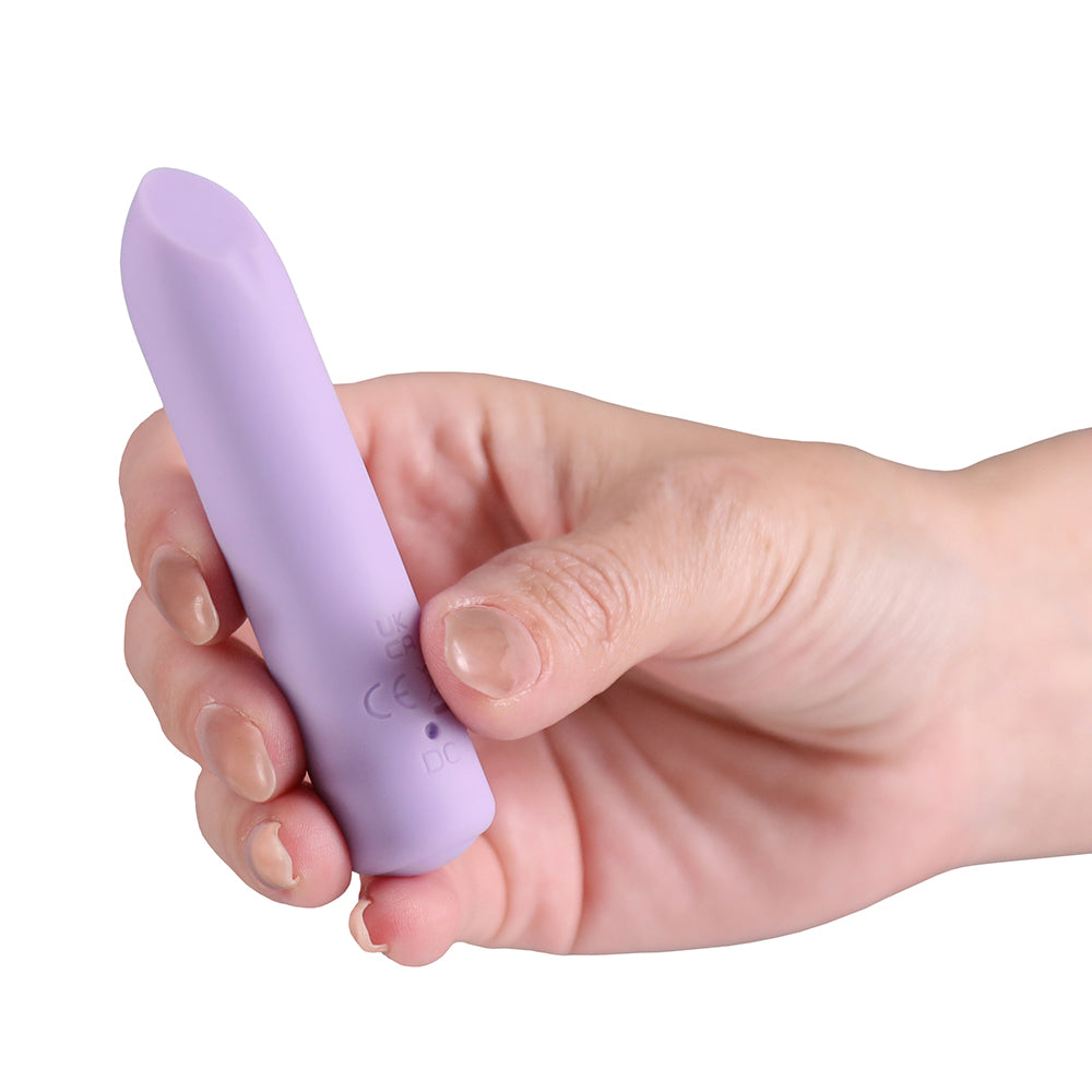 A hand holding a small, smooth, lavender-purple personal massager against a solid white background.