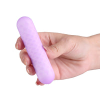 A hand holding a light purple, textured, oval-shaped personal massager against a solid white background.