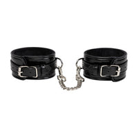 Pair of black leather cuffs with a chain on a white background