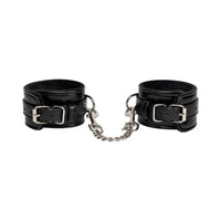 Black leather cuffs with silver buckles and chains on a white background