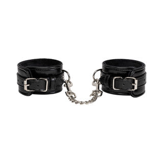 Black leather cuffs with silver buckles and chains on a white background