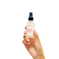 Hand holding a bottle labeled 'mist' against a white background
