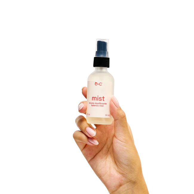 Hand holding a bottle labeled 'mist' against a white background