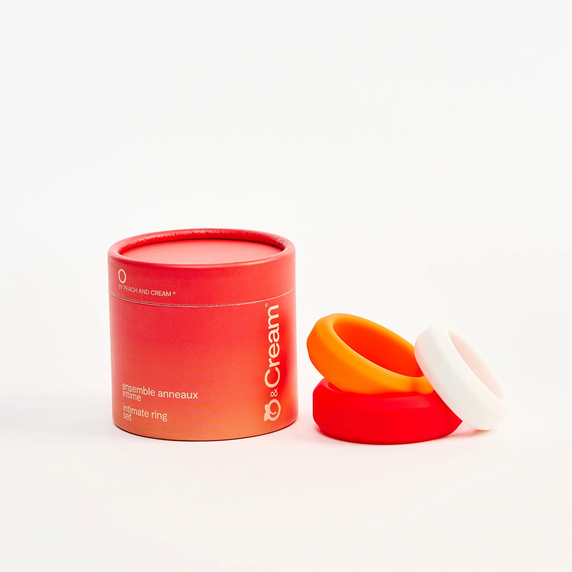 Red container with a white cap and orange cock rings on a white background