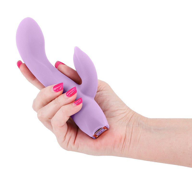 Hand holding a purple vibrator with a white background