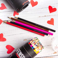 Colorful pencils on a wooden surface with red heart shapes