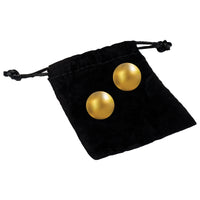 pair of gold kegel balls on top of black toy bag