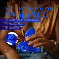 blue vibrating butt plug with rounded head, bottom base, blue gem on bottom, with hand holding the anal plug