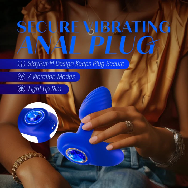 blue vibrating butt plug with rounded head, bottom base, blue gem on bottom, with hand holding the anal plug