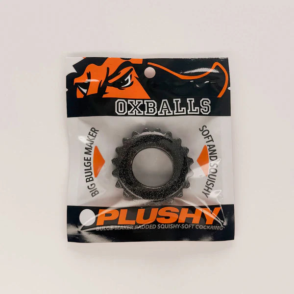 A black textured OXBALLS brand squishy ring in its original retail packaging, featuring a black and orange header card with product text.