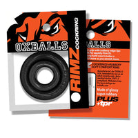 Black OXBALLS RIMZ cockring shown in its retail packaging, with the black rubber ring visible through a clear window and orange-and-black backing card. The packaging also includes a separate orange insert card.