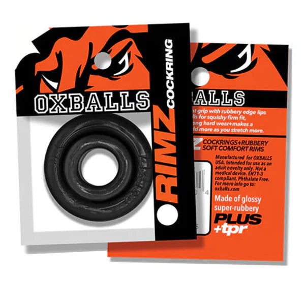 Black OXBALLS RIMZ cockring shown in its retail packaging, with the black rubber ring visible through a clear window and orange-and-black backing card. The packaging also includes a separate orange insert card.
