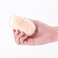 Hand holding a small, clear plastic container with a masturbator inside on a white background
