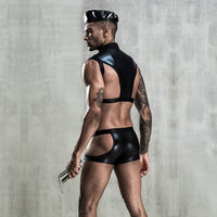 Man wearing a black leather outfit against a gray concrete wall