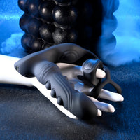 black anal plug, with beads with attached cock ring, beside remote, held in hand