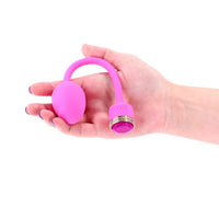 Hand holding a pink sugar vibrating egg on a white background