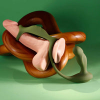 Silicone anal plug with cock ring with wooden base on a green background