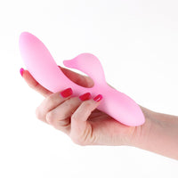 Pink vibrator held in a hand with red nail polish on a white background