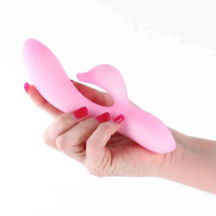 Pink vibrator held in a hand with red nail polish on a white background