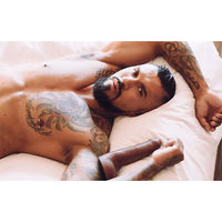 Boomer Banks with tattoos lying on a bed