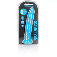 a glow in the dark blue penis shaped dildo with a suction cup base shown in its plastic packaging