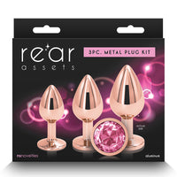 The image features the "Rear Assets Aluminum Metal Anal Plug Kit Circle 3pk by NS Novelties," a set of three anal plugs packaged for retail sale. The plugs are crafted from lightweight aluminum with a chrome-plated finish, adding a touch of elegance and sophistication.