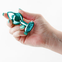 hand holding metal anal plug on white back ground