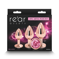The image features the "Rear Assets Aluminum Metal Anal Plug Kit Circle 3pk by NS Novelties," a set of three anal plugs packaged for retail sale. The plugs are crafted from lightweight aluminum with a chrome-plated finish, adding a touch of elegance and sophistication.
