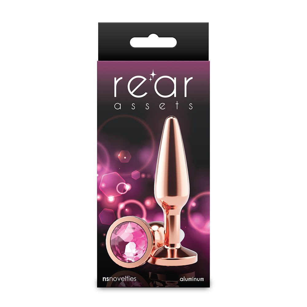 Package of a rose gold butt plug with pink gem, branded 'rear assets', on a white background.