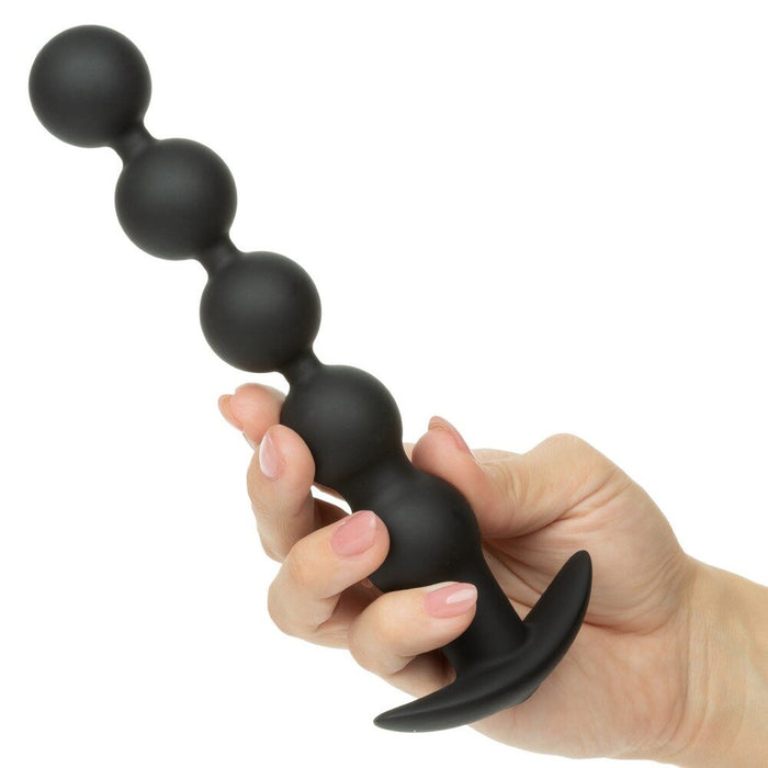 Black power balls held in a hand against a white background