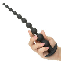 Black silicone anal beads held by a hand on a white background