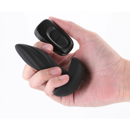 Hand holding a black silicone anal plug with remote on a white background