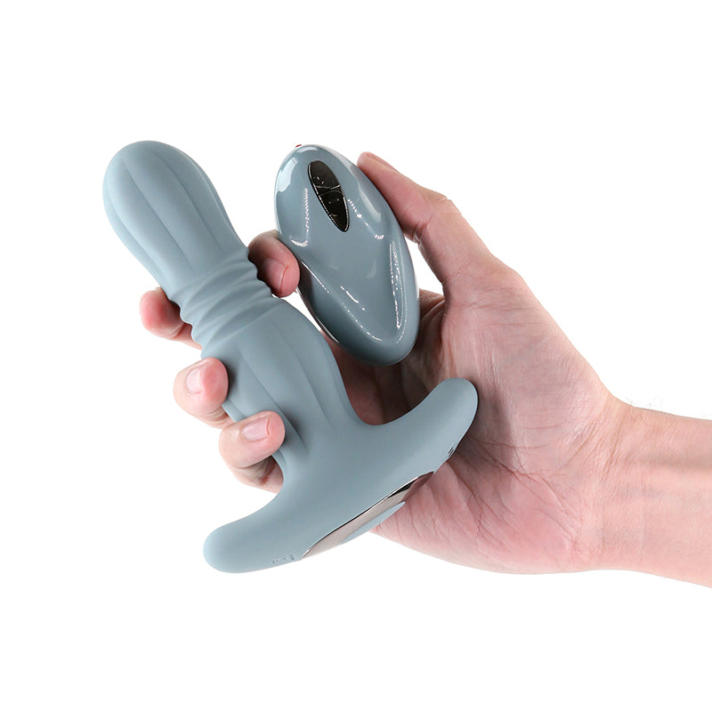 Hand holding a gray silicone anal plug against a white background
