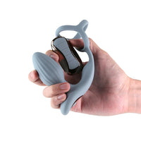 hand holding grey vibrating and gyrating anal plug with attached cock ring and remote