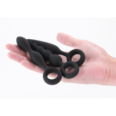 3 anal plugs with finger rings held in hand on a white back ground