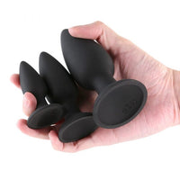 Hand holding Renegade Triple Strike anal plugs on a white background