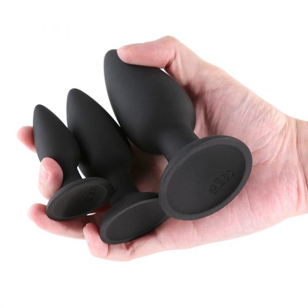 Hand holding Renegade Triple Strike anal plugs on a white background