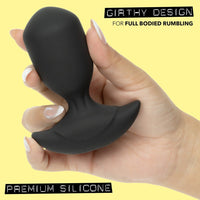 Hand holding a black silicone anal probe with 'Girthy Design' text on a yellow background