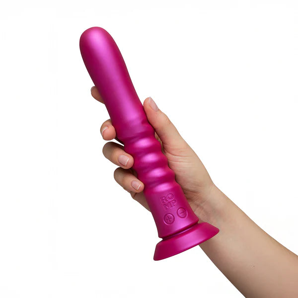 Pink handheld massager held by a hand on a white background