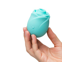 Hand holding a turquoise rose-shaped object against a white background