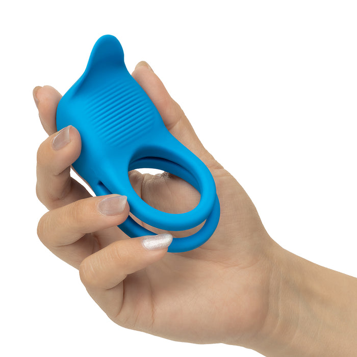 A bright blue silicone ring-shaped hand-held device with a textured grip, shown being held by a hand against a plain white background.