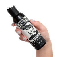 Hand holding a bottle of Lube Tube semen lube with black and white design.