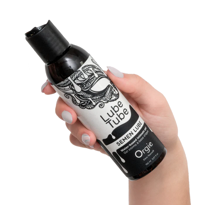 Hand holding a bottle of Lube Tube semen lube with black and white design.
