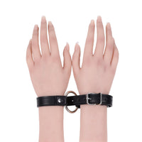 Black leather collar cuffs with a ring on a white background