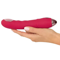 Pink and rose gold vibrator held in a hand on a white background