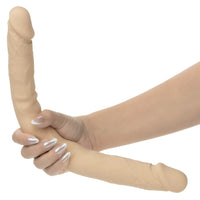 Beige silicone double dildo on a hand against a white background