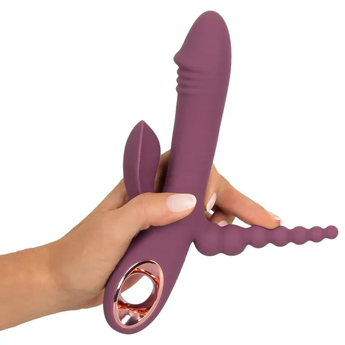 Purple triple stimulation vibrator held by a hand on a white background