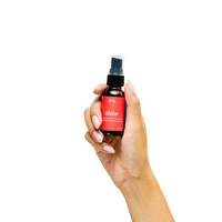 Hand holding a small spray bottle of slow calming with a red label on a white background