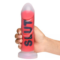 hand holding clear and red dildo with the word slut in black up the shaft with bottom base