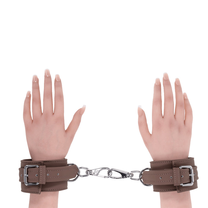 2 hands wearing brown handcuffs on wrists